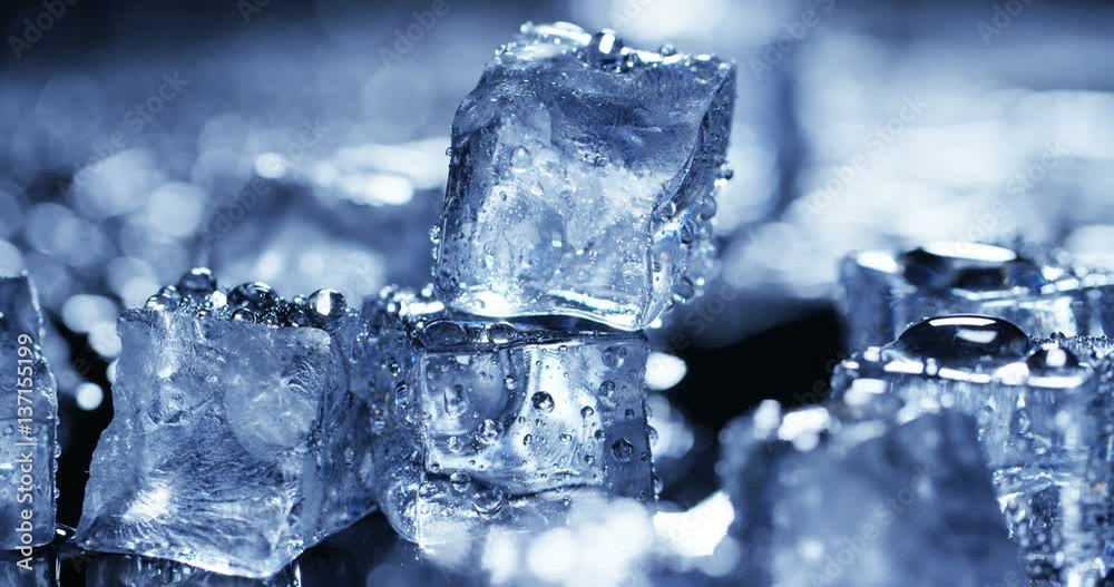 Macro shot of pure water ice cubes that melt in slow motion on blue background. Concept: pure mountain spring water, ice, cocktails, fresh and frozen products.