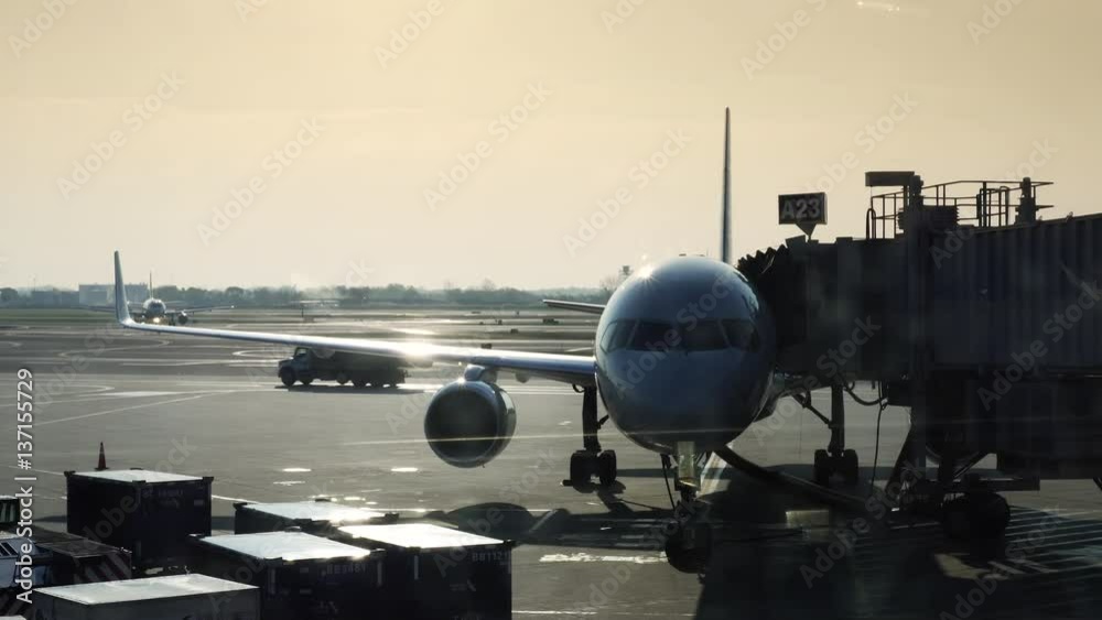 Airplane parked at an airport with passenger gangway, at sunrise