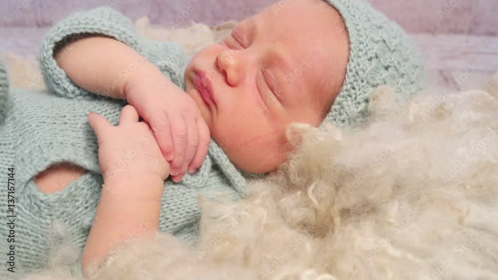 Adorable kid wrinking and moving his lips in his sleep, dressed in a knitted outfit