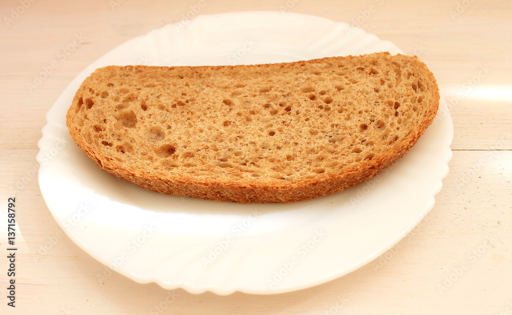 Slice of dark bread with bran on the white plate