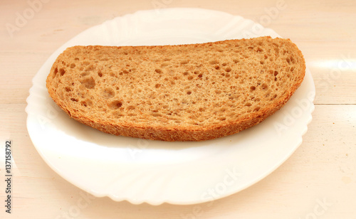 Slice of dark bread with bran on the white plate