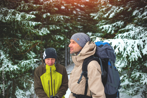 Friends with backpacks in the forest in winter.