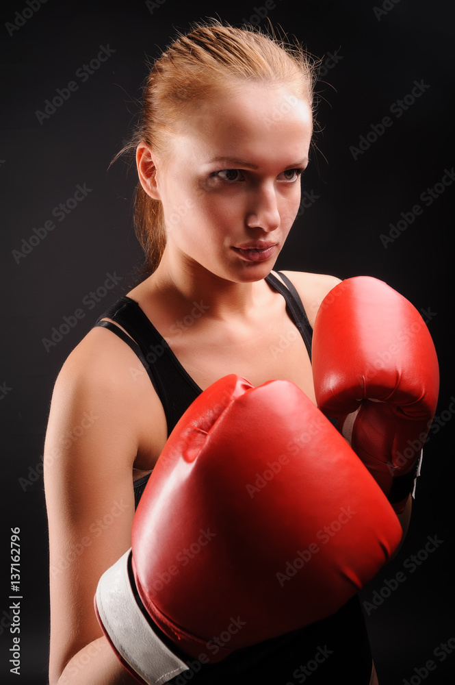 Young attractive woman with boxing gloves at black background Young attractive woman with boxing gloves at black background