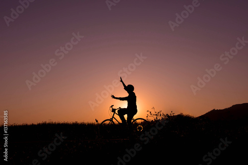 Silhouette of happy person on bicycle in natural sunset