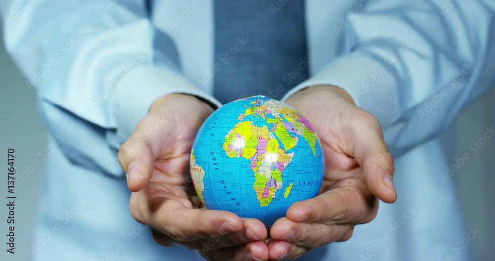 The young businessman holding in his hands a model of a globe with graphics.Concept of global business and communication,power of sharing,worldwide marketing,international finance, internet connection The young businessman holding in his hands a model of a globe with graphics.Concept of global business and communication,power of sharing,worldwide marketing,international finance, internet connection
