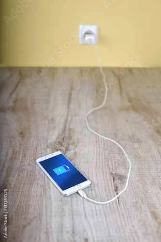 Mobile smart phones charging on wooden desk