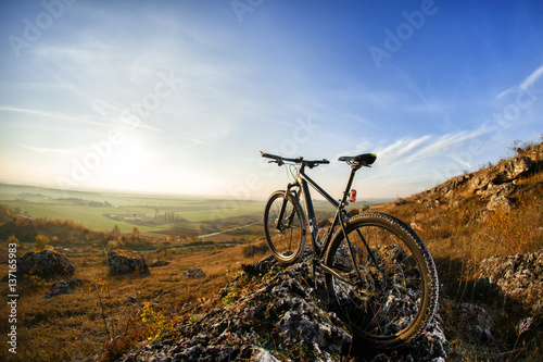 Mountain bicycle on hill under blue sky with clouds.
