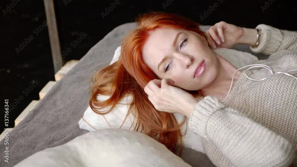 Portrait of young woman relaxing in bed and listening to music with headphones Portrait of young woman relaxing in bed and listening to music with headphones