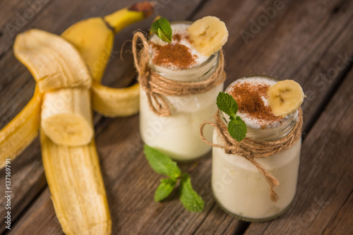 Organic homemade sweet milk dessert with banana, cinnamon and mint on the wooden table