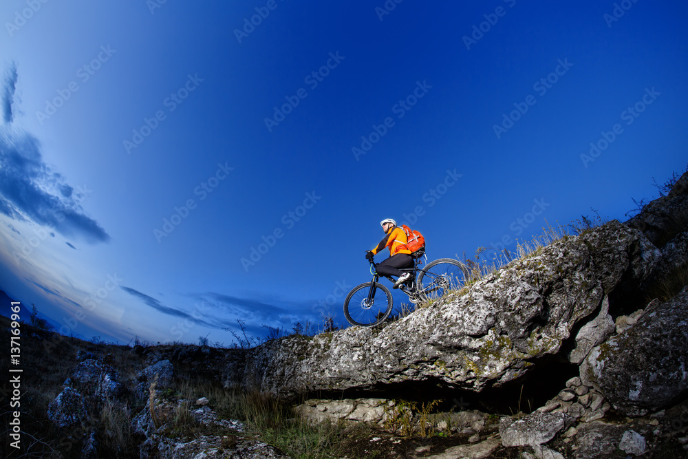 Cyclist Riding the Bike Down Hill on the Mountain Rocky Trail at Sunset. Extreme Sports