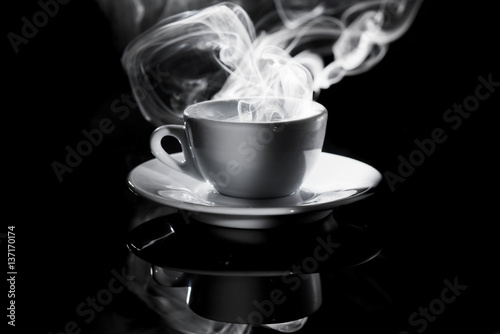 small white cup of steaming coffee on a black background