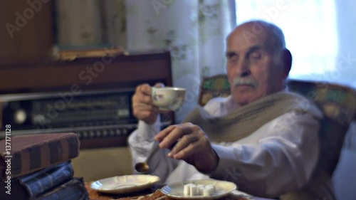 Old Man Drinks Tea Pile of Books on the Table Elderly Professor Has Breakfast Sitting at the Table in Cosy Room Vintage Radiogram is Behind Cold Day at Home