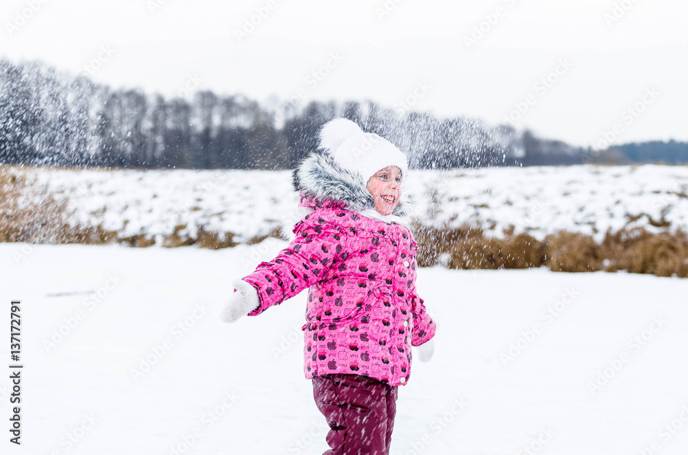 Little girl throwing snow in the winter in nature
