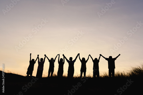 Silhouette of happy team making high hands in sunset sky background