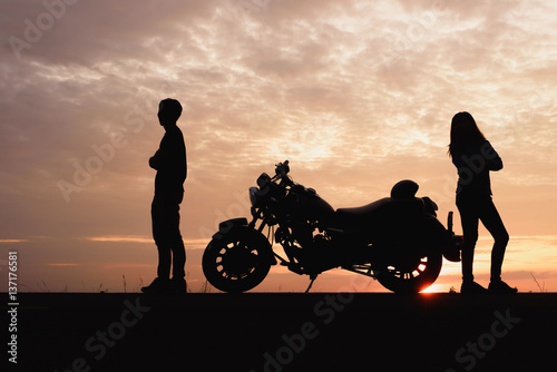 Photos Silhouette of couple are quarrel with a motorcycle at sunset background