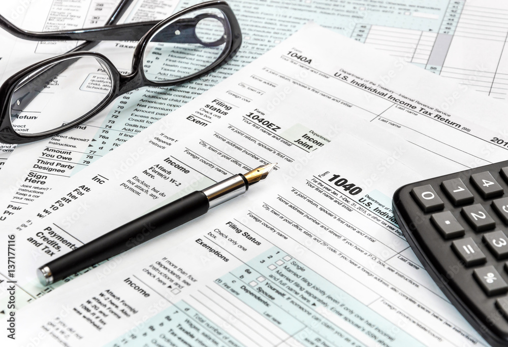 Calculator, glasses and pen on tax form 1040. Calculator, glasses and pen on tax form 1040.