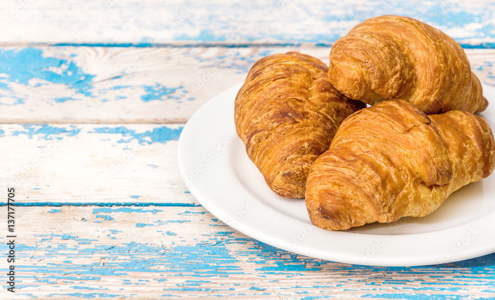 Plate with croissants on the blue wooden table. Plate with croissants on the blue wooden table.