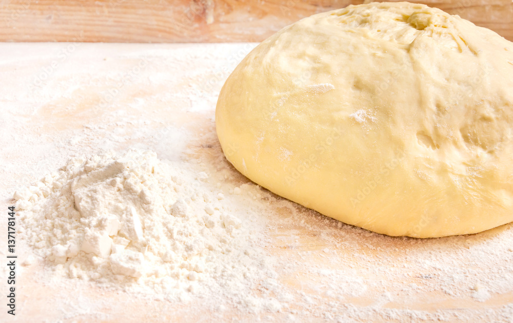 Dough with a pile of flour on a wooden background. Dough with a pile of flour on a wooden background.
