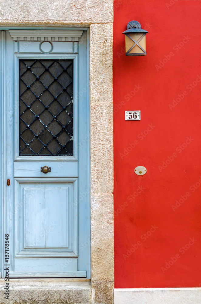 old blue wooden door in composition with a vivid red painted wall. A beautiful combination of colours in a building located in the traditional colorful and awarded village of Crete, Archanes. old blue wooden door in composition with a vivid red painted wall. A beautiful combination of colours in a building located in the traditional colorful and awarded village of Crete, Archanes.
