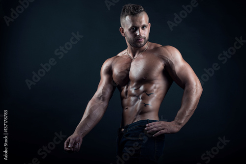 Young attractive muscular male fitness model demonstrates his perfect body