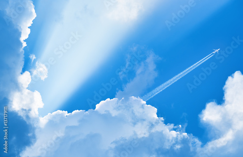 Airplane flying in the blue sky among clouds and sunlight photo