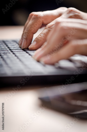 Closeup of business woman hand typing on laptop keyboard, lighting effect