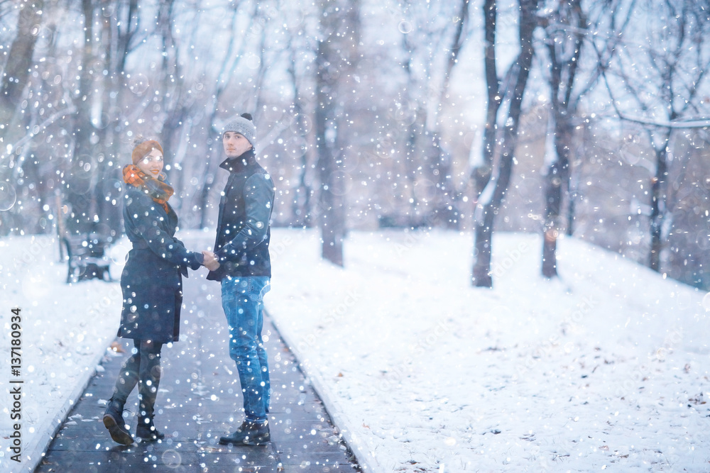 young man and woman in the snow in a city park couple winter