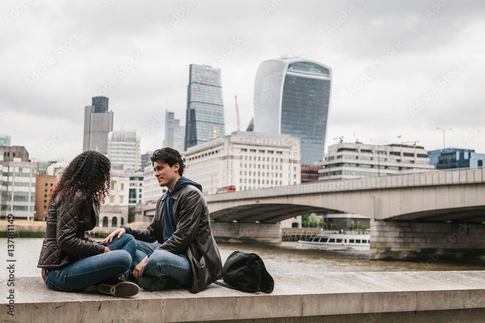 Multi-ethnic couple sitting in the River Thames pier Multi-ethnic couple sitting in the River Thames pier
