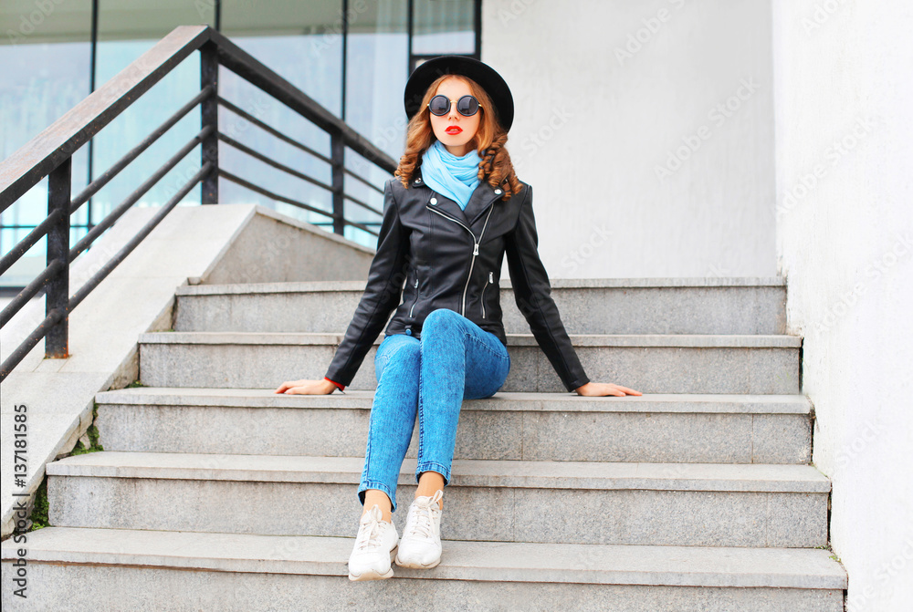 Fashion pretty woman wearing black rock jacket, hat in city Fashion pretty woman wearing black rock jacket, hat in city