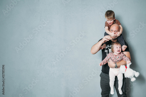 stressed young dad with two small children in his arms photo