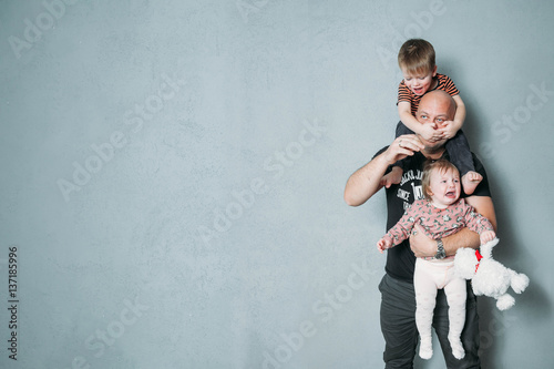 stressed young dad with two small children in his arms