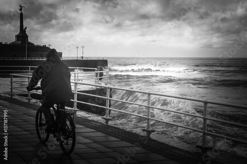 Cyclist on the seafront during a storm.