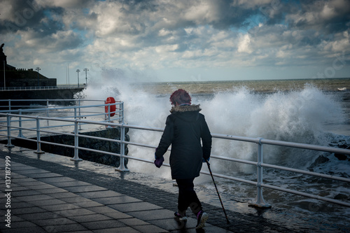 A woman walk along the seafront during a storm.