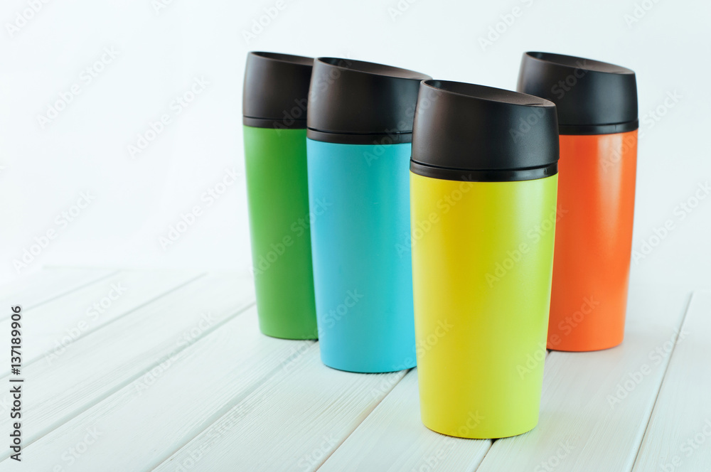 Color thermos mugs on the white wooden table Color thermos mugs on the white wooden table