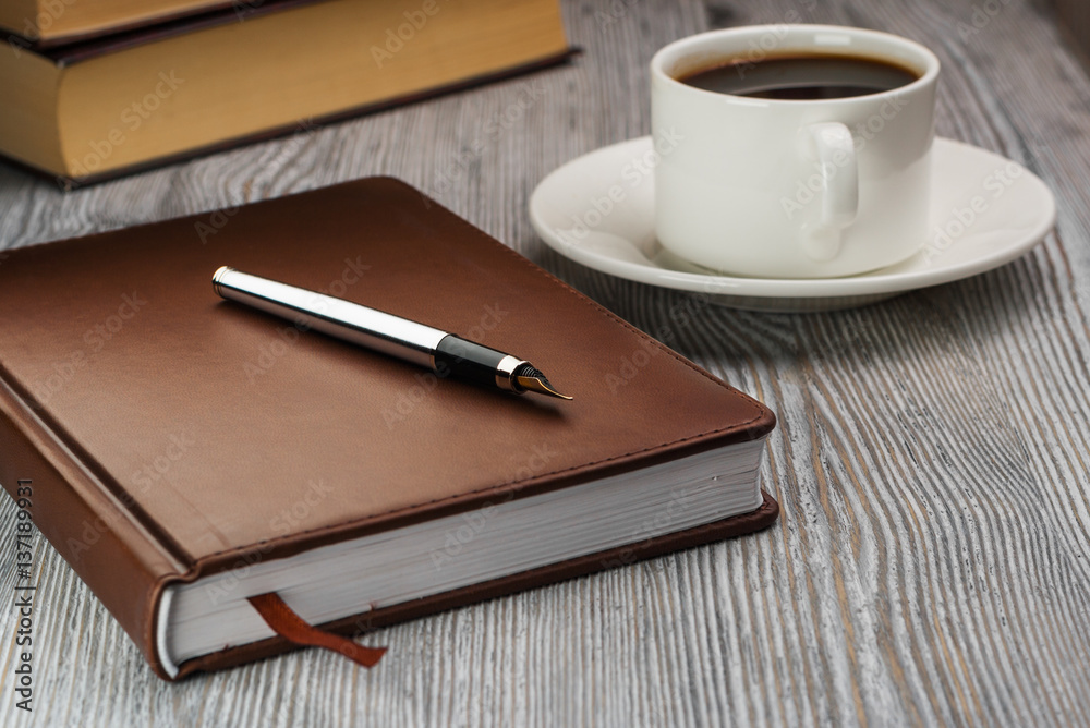 Closed notebook with fountain pen on rustic table. Pen on notebook. Closed notebook with fountain pen on rustic table. Pen on notebook.