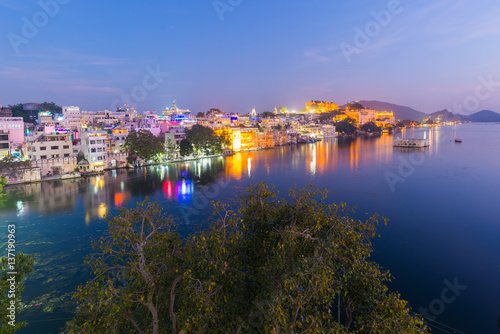 Glowing cityscape at Udaipur at dusk. The majestic city palace reflecting lights on Lake Pichola, travel destination in Rajasthan, India
