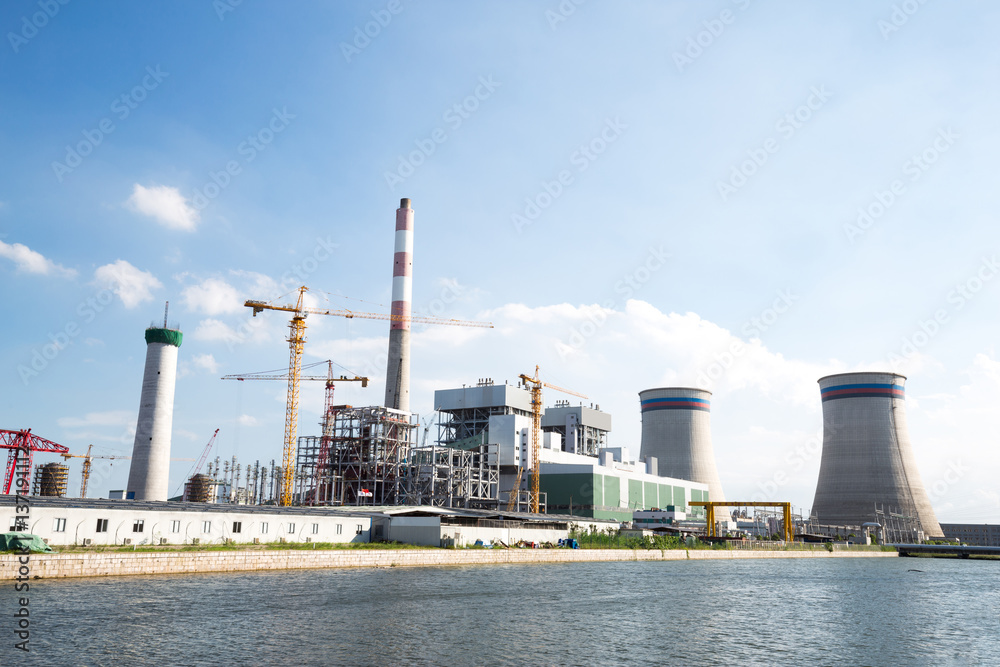 modern power plant near river in blue sky