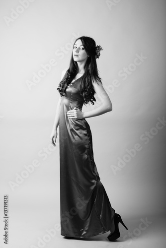 Portrait of excited attractive lovely woman in long dress on light background.