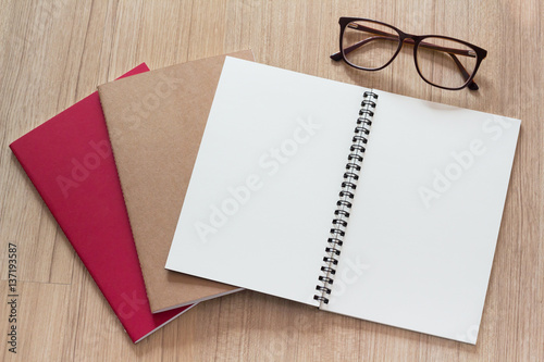 blank page of note book with eye glasses on wooden table background