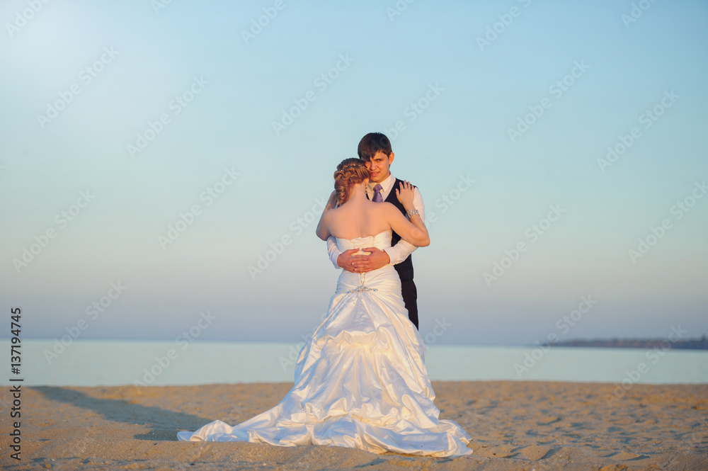 bride and groom walking on the sand on the shore