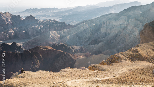 Woman backpacker tourist sitting resting mountain edge desert landscape.