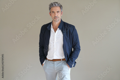 Handsome mature man standing on grey background, isolated