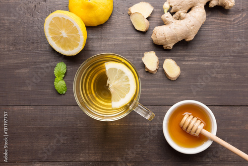 Cup of ginger tea with lemon, ginger, honey on wooden background
