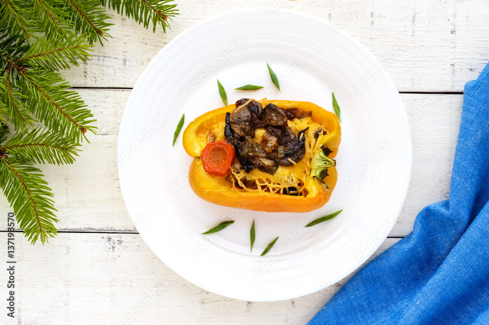 Yellow bell peppers stuffed with mushrooms, vegetables and cheese on a plate on a white background. The top view Yellow bell peppers stuffed with mushrooms, vegetables and cheese on a plate on a white background. The top view