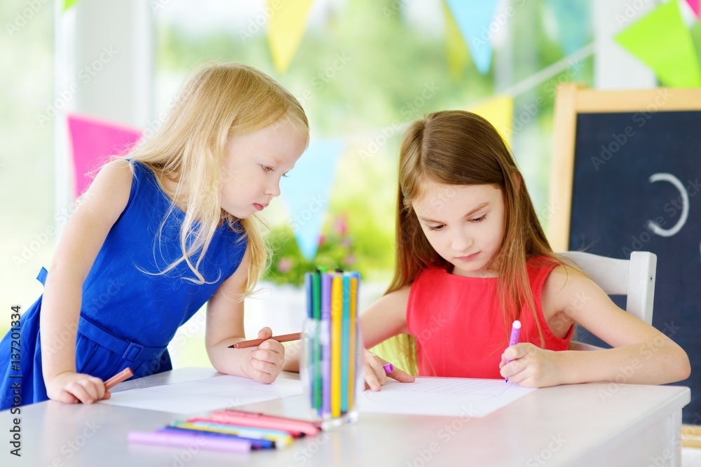 Two cute little sisters drawing with colorful pencils at a daycare Two cute little sisters drawing with colorful pencils at a daycare