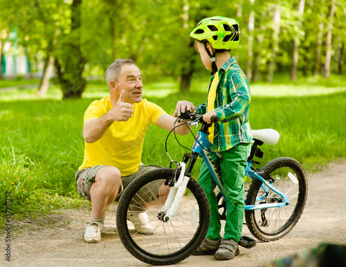 Grandfather talking with his grandson riding a bicycle