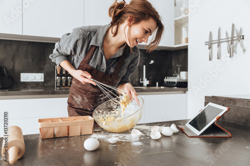 Cheerful woman cooking and looking at tablet computer. photo