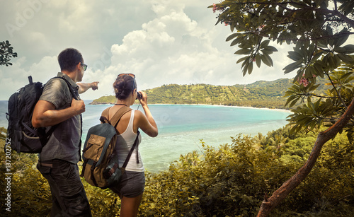 Travellers with backpacks watching through binoculars enjoying views coast photo