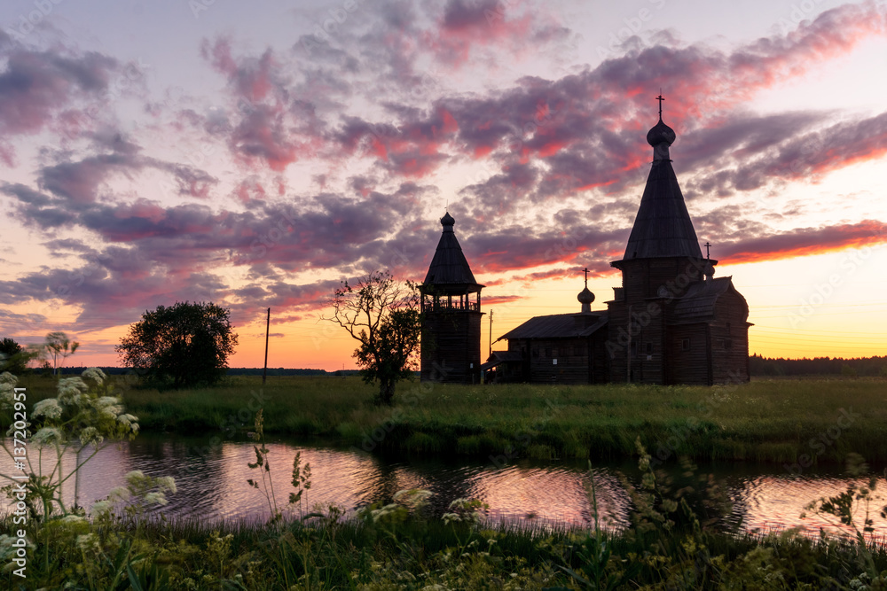 Fototapeta premium Ancient wooden church in Saunino village near Kargopol at sunrise, Russia