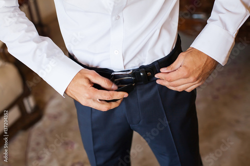 Man corrects belt, fees groom, man's hands, dressing, man buttons pants, jeans